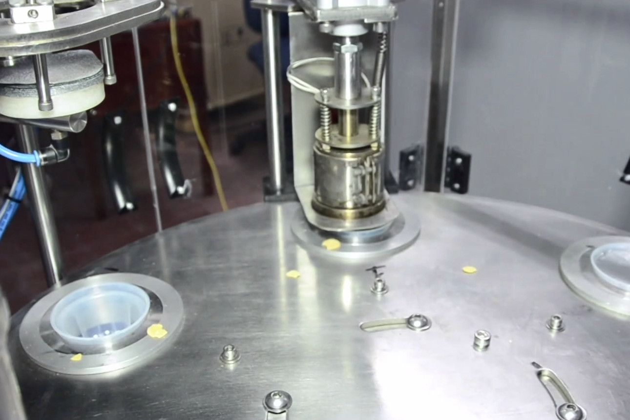 Primer plano de los vasos de acero inoxidable en la tornamesa de la llenadora rotativa.
