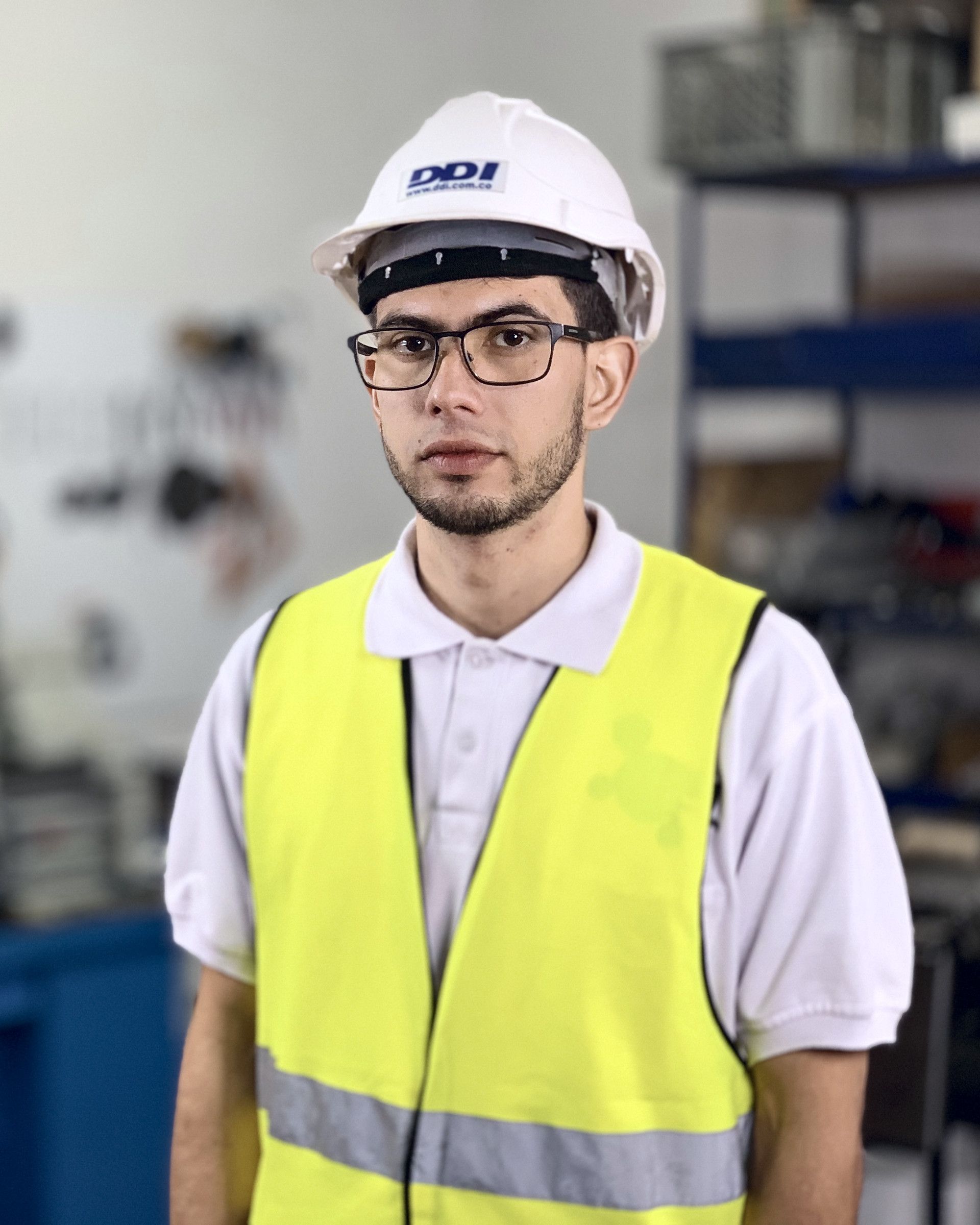 Ingeniero de DDI con casco y chaleco en el taller.